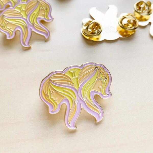 Gemini Pin in pastel colors and gold enamel on light wood table