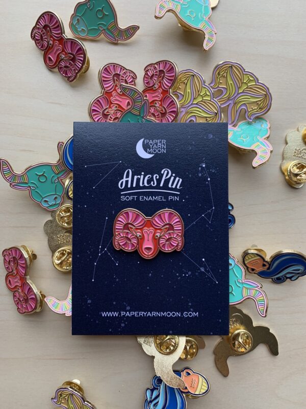 Aries Pin in red with gold enamel. Set in black card backing with pins surrounding it.