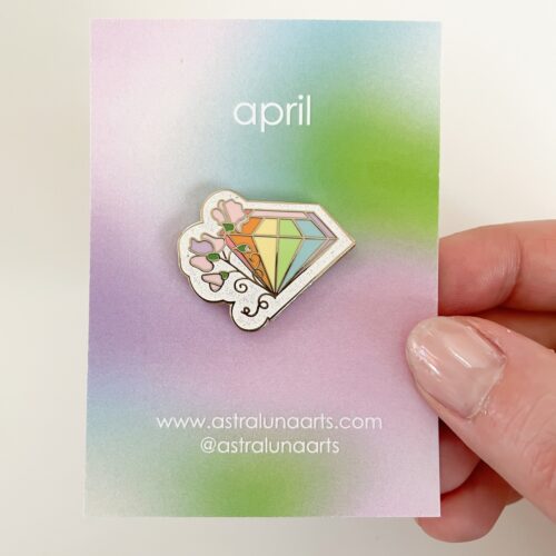April Pin featuring sparkly diamond with rainbow and sweet pea flower.