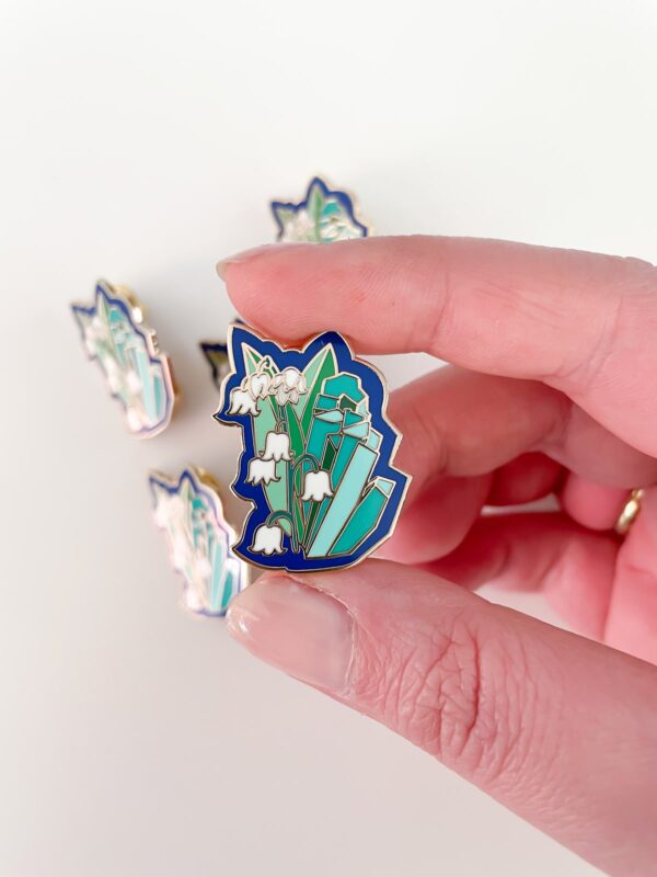 May birth month pin with emerald stone and lily of the valley flower, set in gold enamel. in hand created by Astraluna Arts.